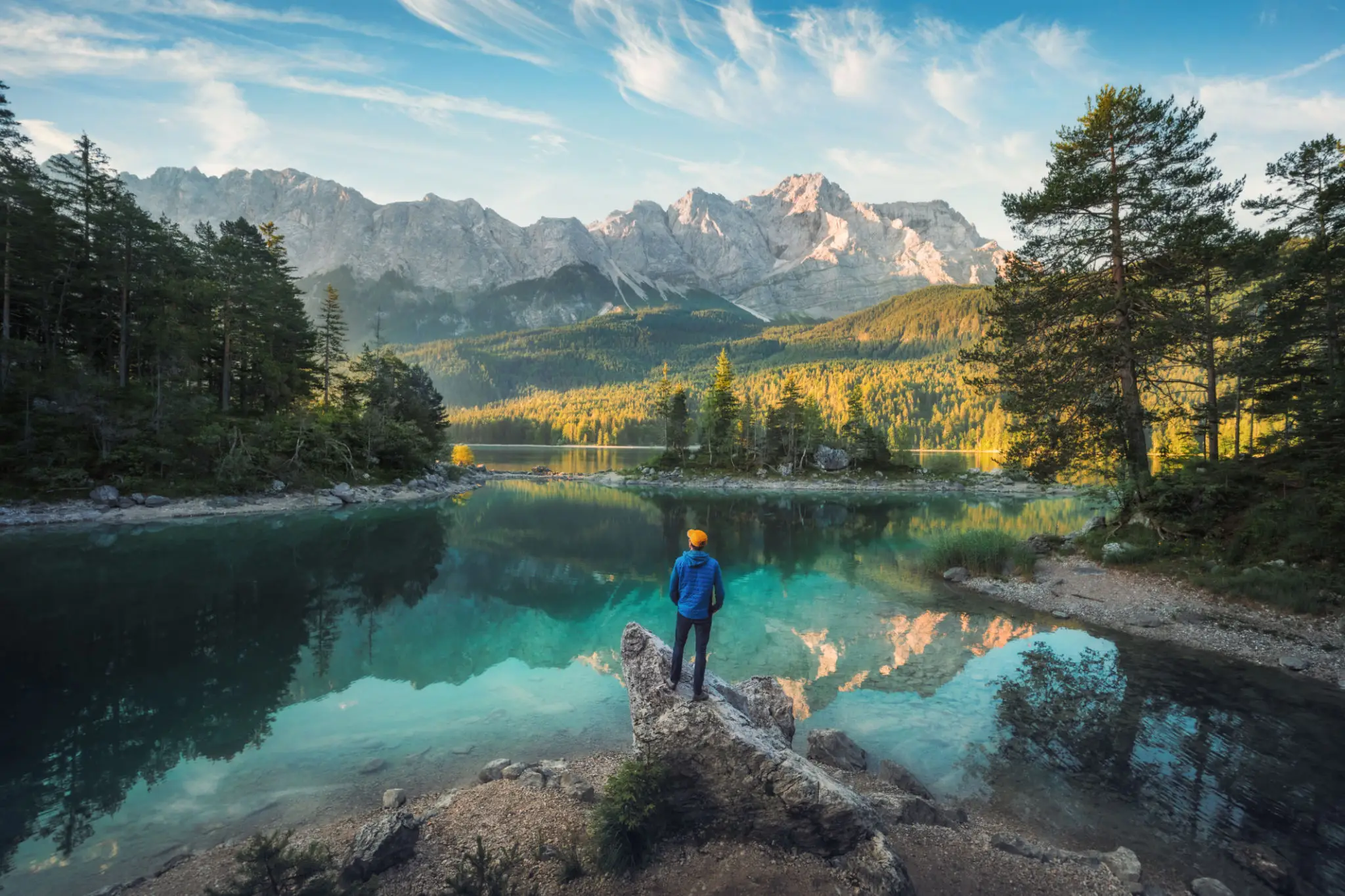 Hiker overlooking alpine lake with mountain reflections